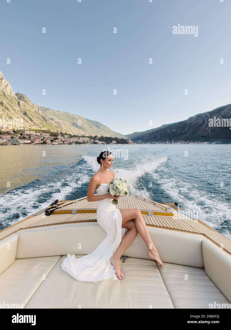 Budva, Montenegro - 08 agosto 2023: Sposa con un bouquet di fiori seduto a poppa di uno yacht che naviga sul mare Foto Stock
