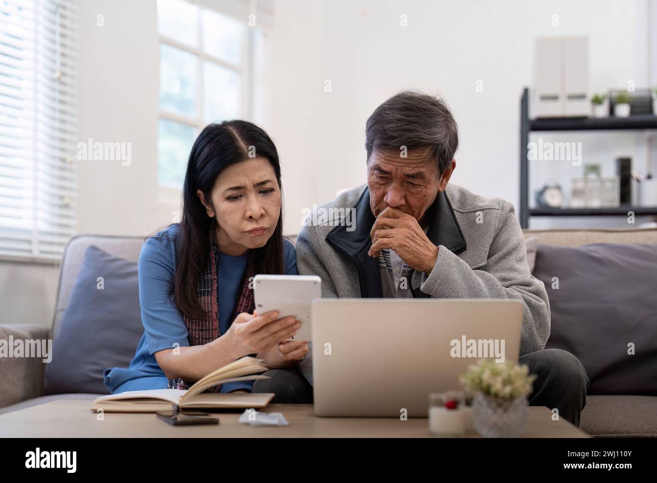 Grave stress asiatico anziani coppia preoccupata per la fattura discutere non pagato debito bancario pagamento carta preoccupazione per problema di denaro Foto Stock