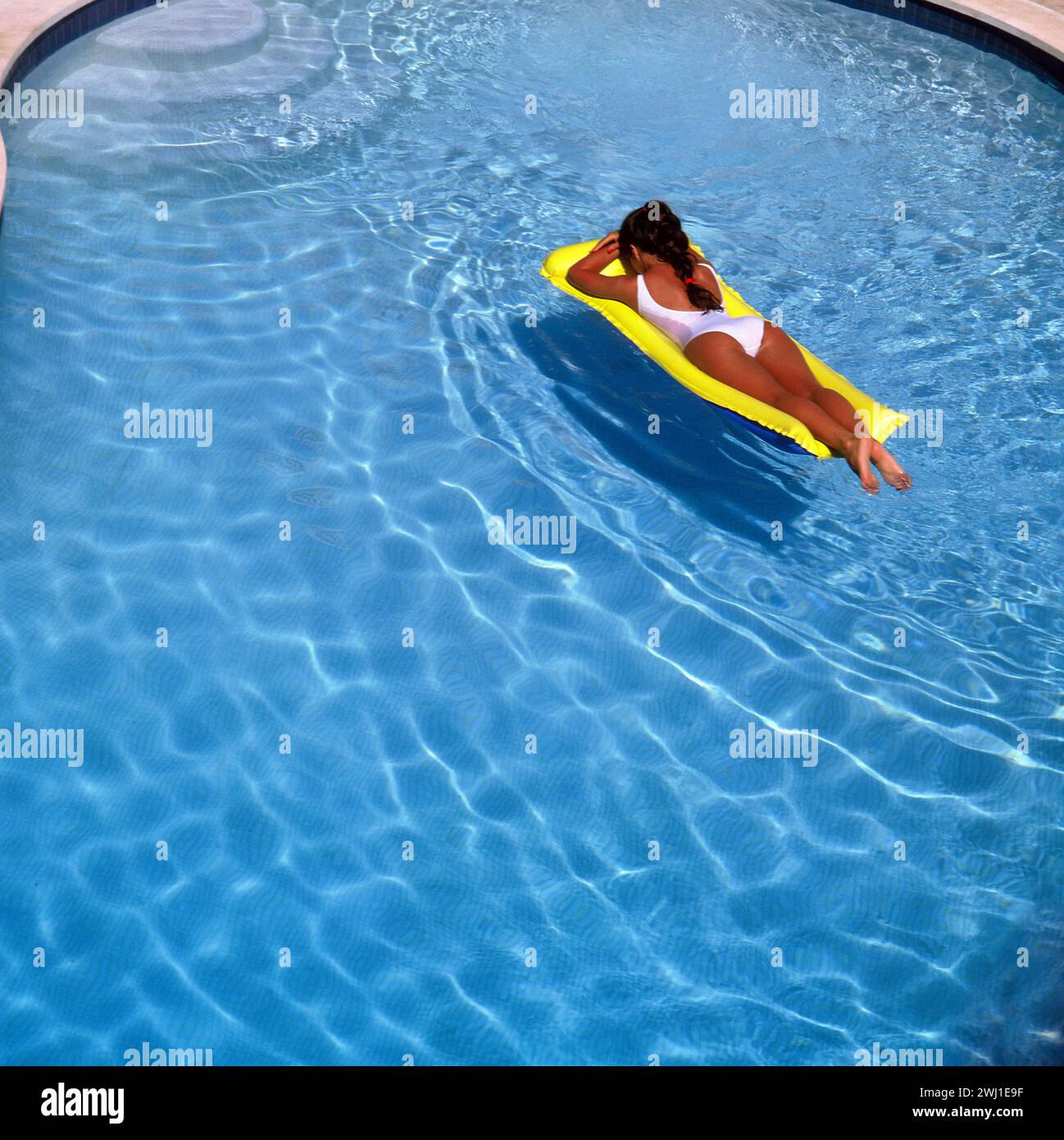 Spagna. Giovane donna in costume da bagno sdraiata sul lettino in piscina. Foto Stock
