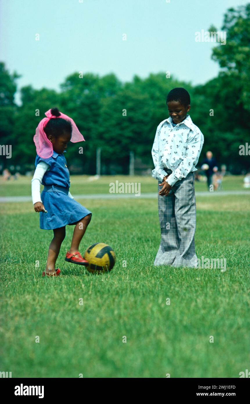 Inghilterra. Londra. Clapham Common. Bambini. Bambina e ragazzo che giocano a football nel parco. Foto Stock
