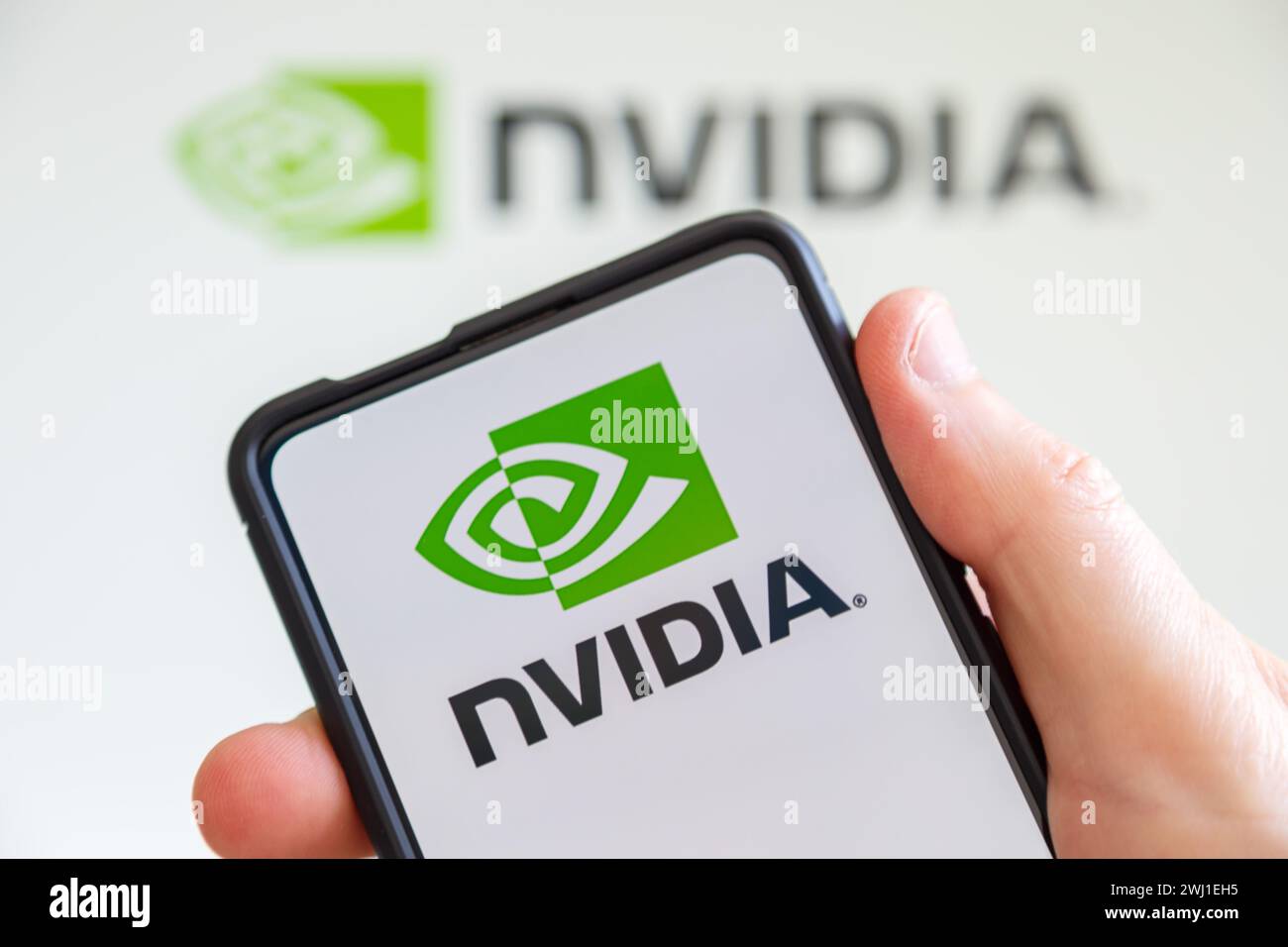 Tenere a mano il telefono cellulare con il logo Nvidia dello sviluppatore di processori grafici schermo del computer Foto Stock