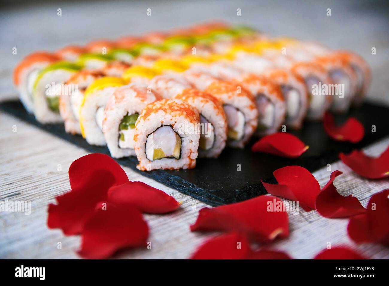 Sushi roll giapponesi assortiti su sfondo nero. Cornice alimentare asiatica o giapponese Foto Stock