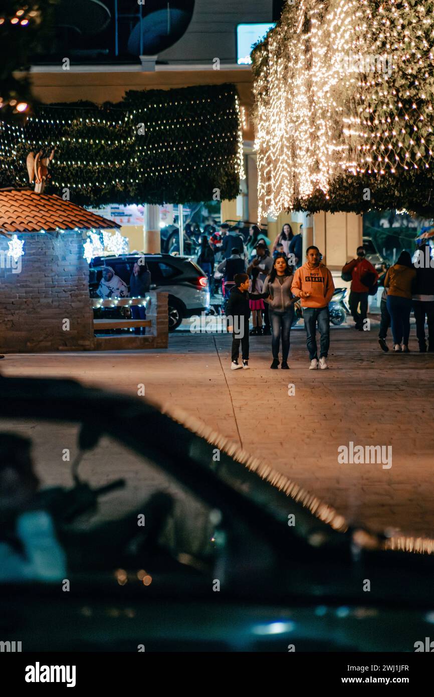 Un gruppo di persone che cammina con le luci di Natale illuminate su un marciapiede, Tuxpan Jalisco Foto Stock