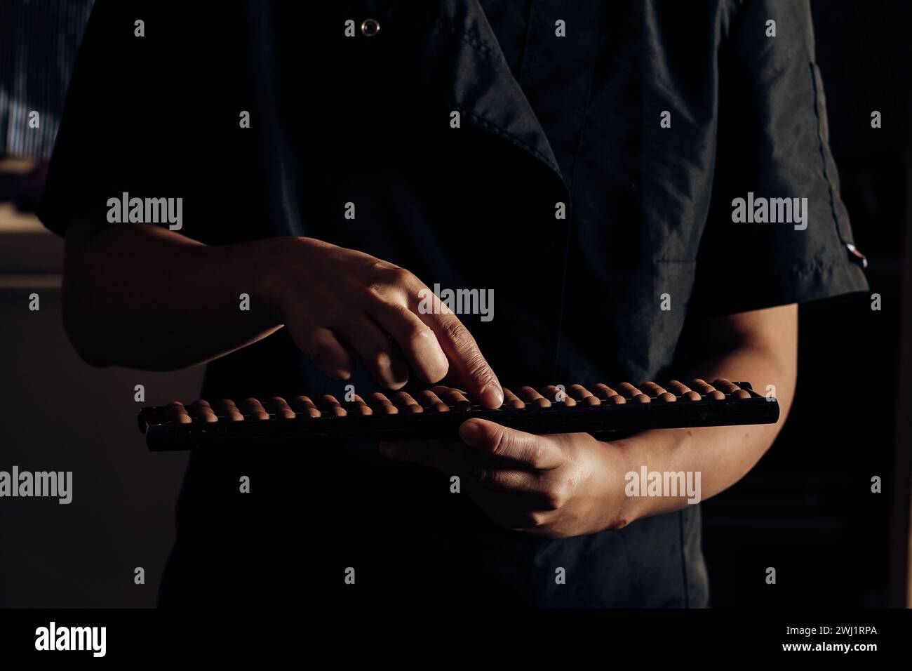 Donna in abito nero che usa sapientemente un abaco cinese per calcoli matematici, mostrando competenza e concentrazione Foto Stock