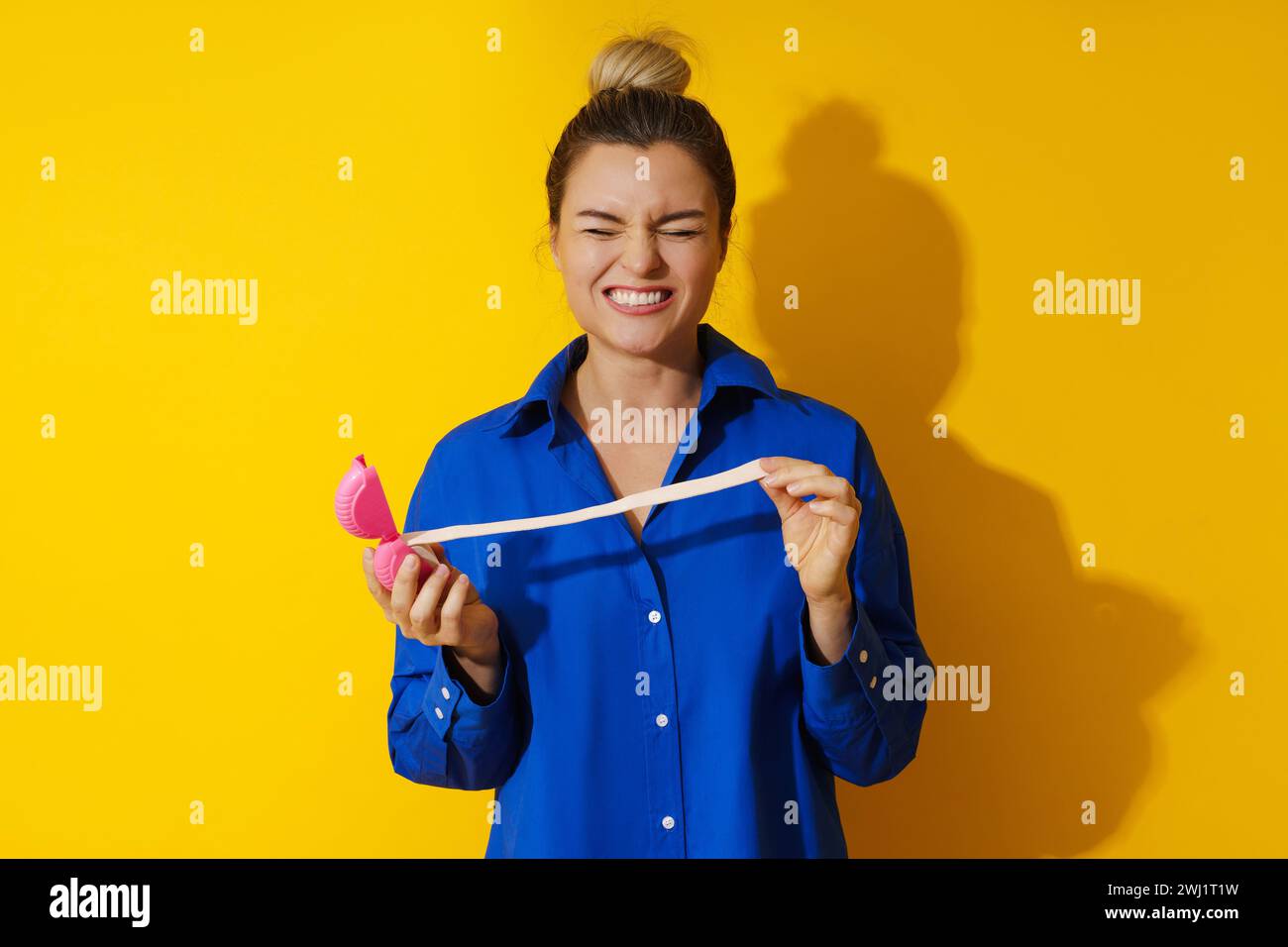 Giovane donna che assaggia gomma da masticare acida su sfondo giallo Foto Stock
