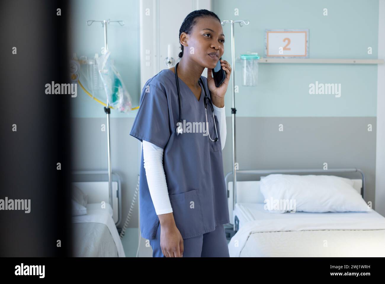 Medico donna afroamericana che parla su smartphone in camera d'ospedale Foto Stock