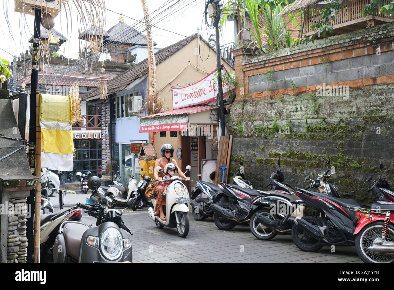 Madre e bambino occidentali su uno scooter nel centro di Ubud, nel centro di Bali, Indonesia Foto Stock