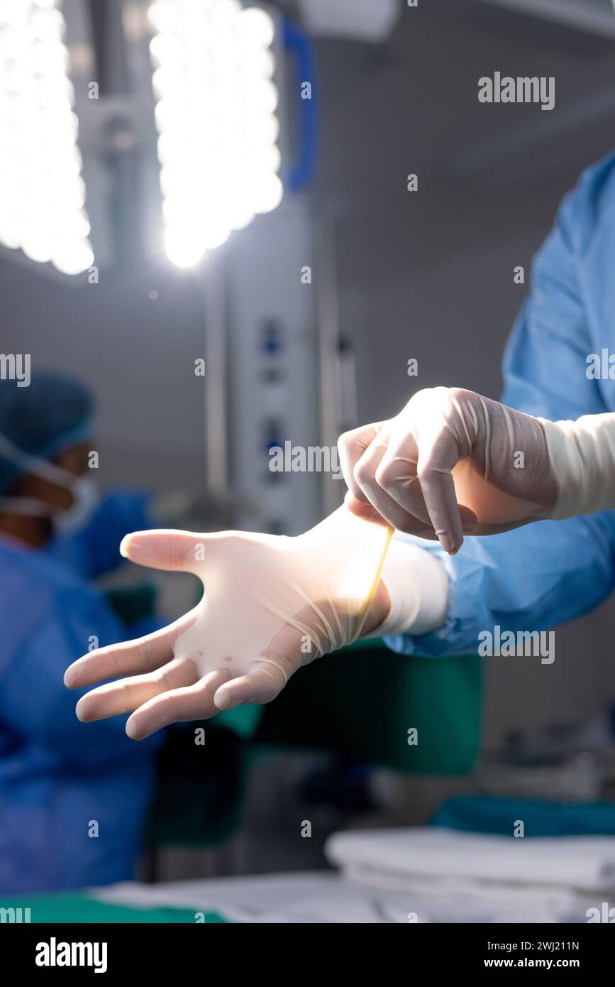 Mani del medico asiatico femminile che indossa guanti protettivi nella sala operatoria dell'ospedale Foto Stock