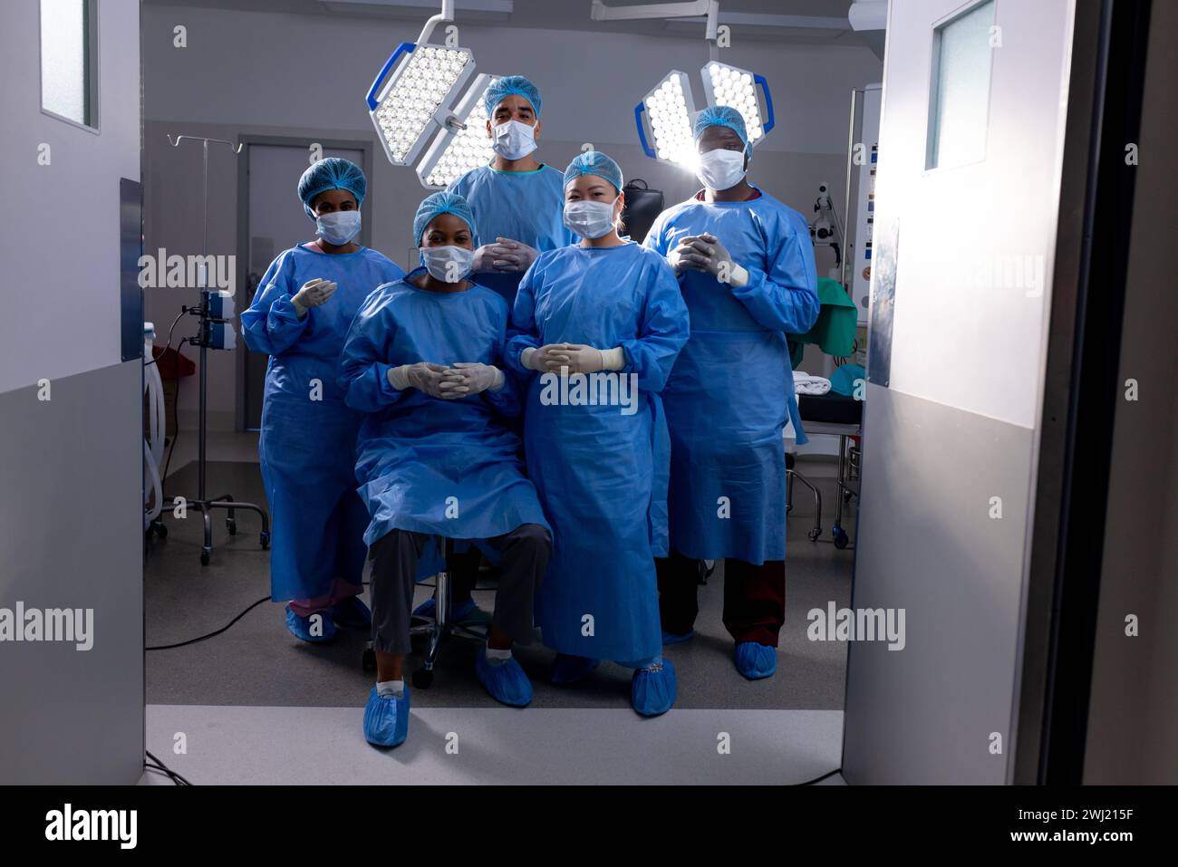 Ritratto di diversi medici maschili e femminili che indossano maschere facciali in sala operatoria dell'ospedale Foto Stock