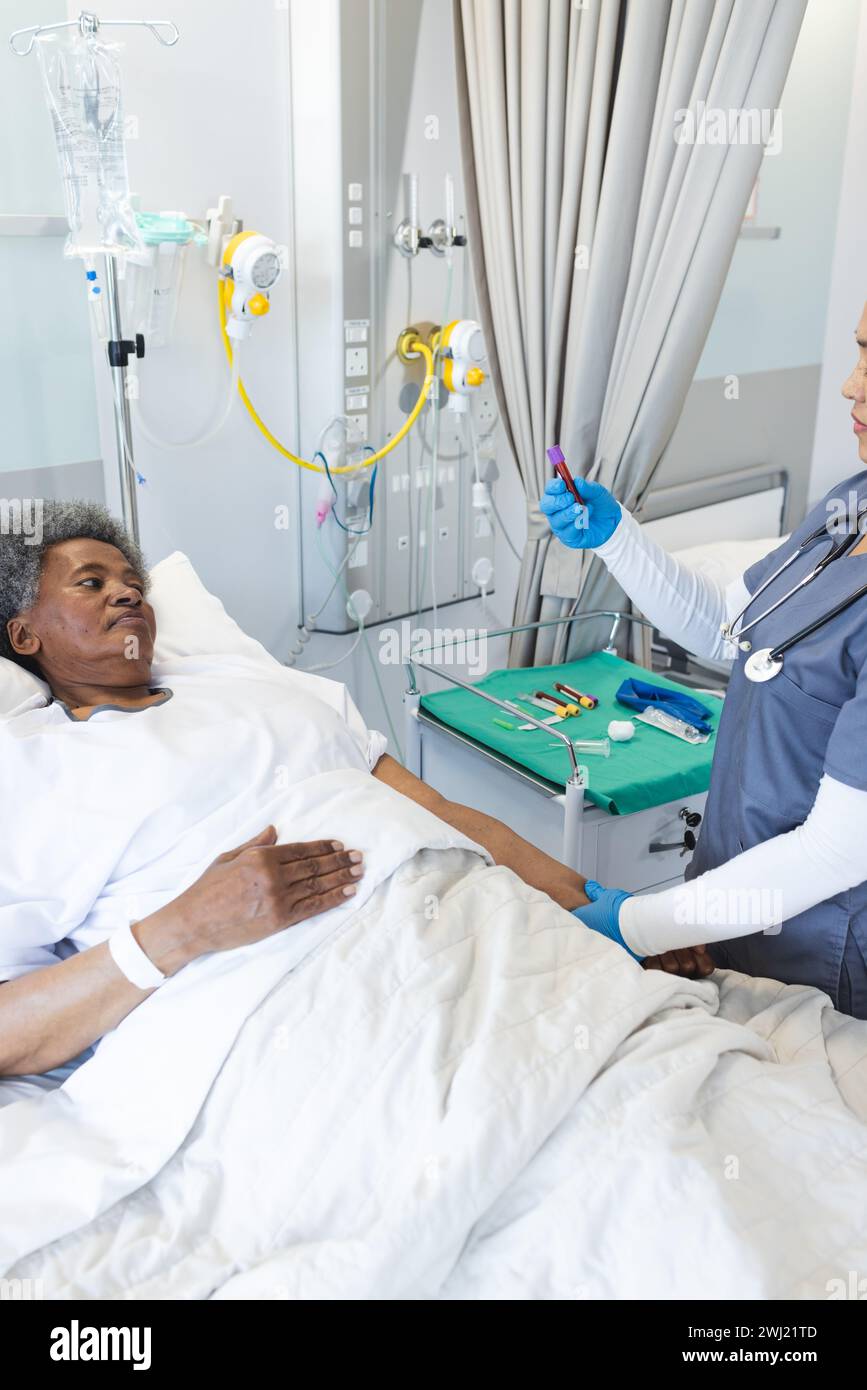 Medico femminile diversificato e paziente anziano in camera d'ospedale Foto Stock