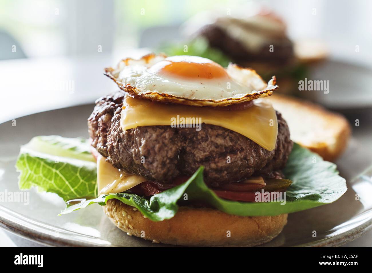 Deliziosi cheeseburger fatti in casa guarniti con un uovo perfettamente fritto con il lato alto Foto Stock