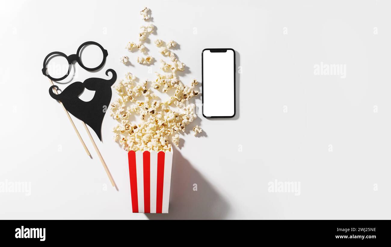 Deliziosi popcorn, oggetti di scena per le feste e smartphone con schermo vuoto per il tuo design Foto Stock