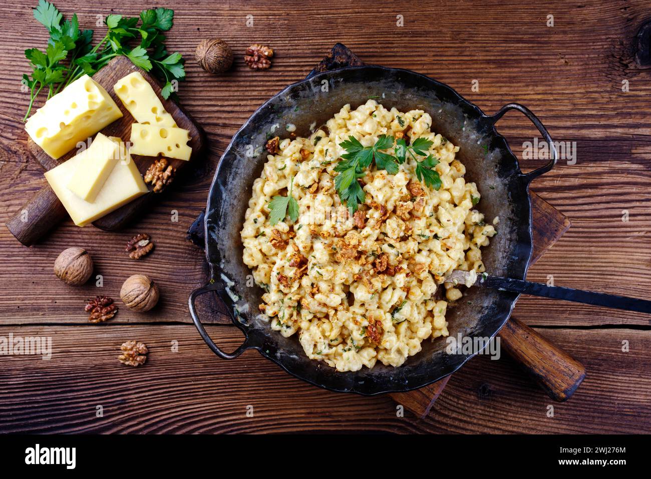 Tradizionale AllgÃ¤uer KÃ¤sespÃ¤tzle con noci servito come primo piano in una padella in ferro battuto su un r Foto Stock