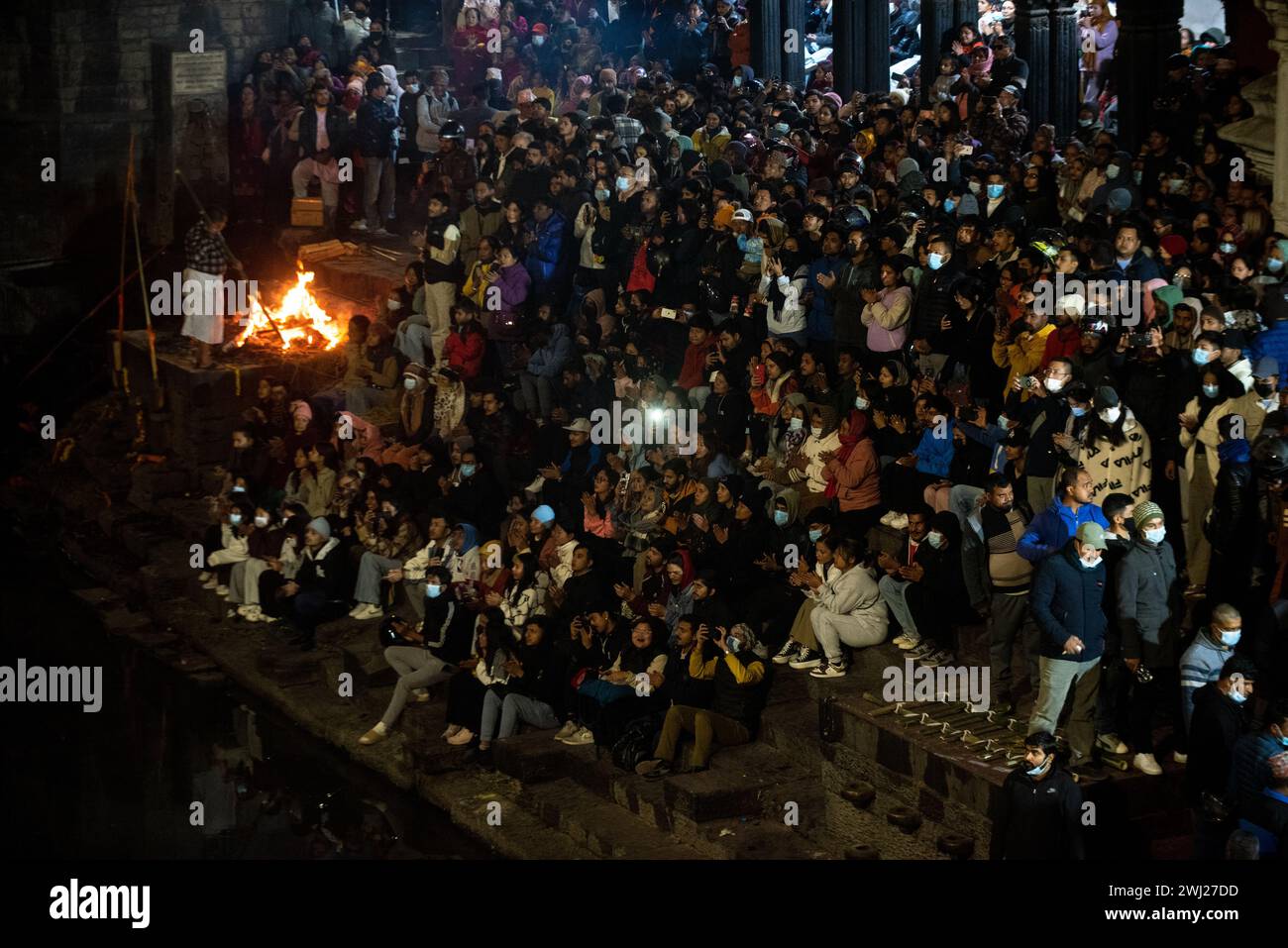 I devoti indù si riuniscono all'interno dei locali del tempio di Pashupatinath, sulla riva del sacro crematorio del fiume Bagmati, luogo dove ascoltare la preghiera del lunedì sera, che è il giorno del Signore Shiva, Kathmandu, Nepal, lunedì 12 febbraio 2024 Foto Stock