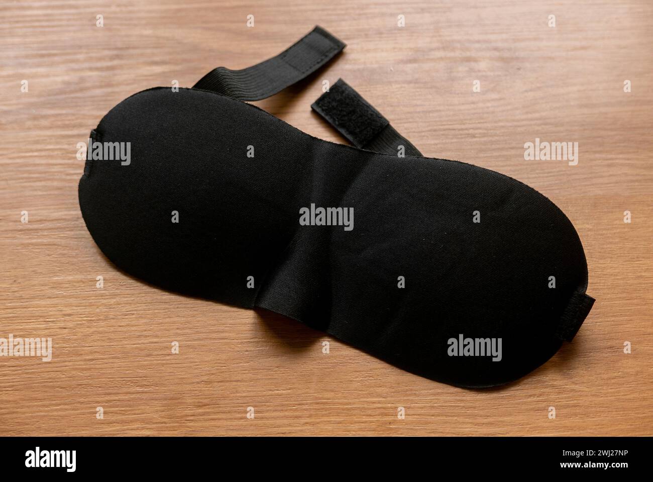 Maschera per gli occhi dormienti nera su tavolo in legno. Foto Stock