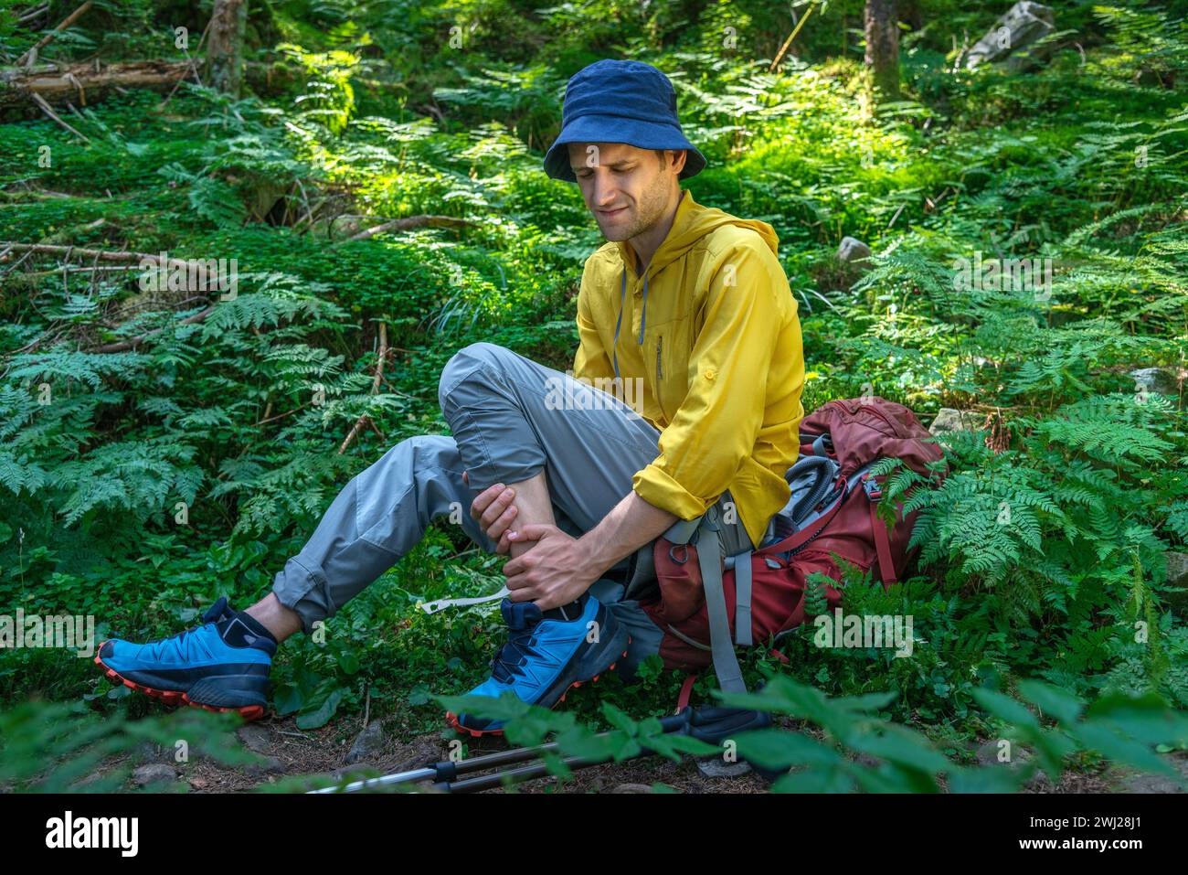 L'uomo con zaino ha problemi con la caviglia spruzzata nella foresta Foto Stock