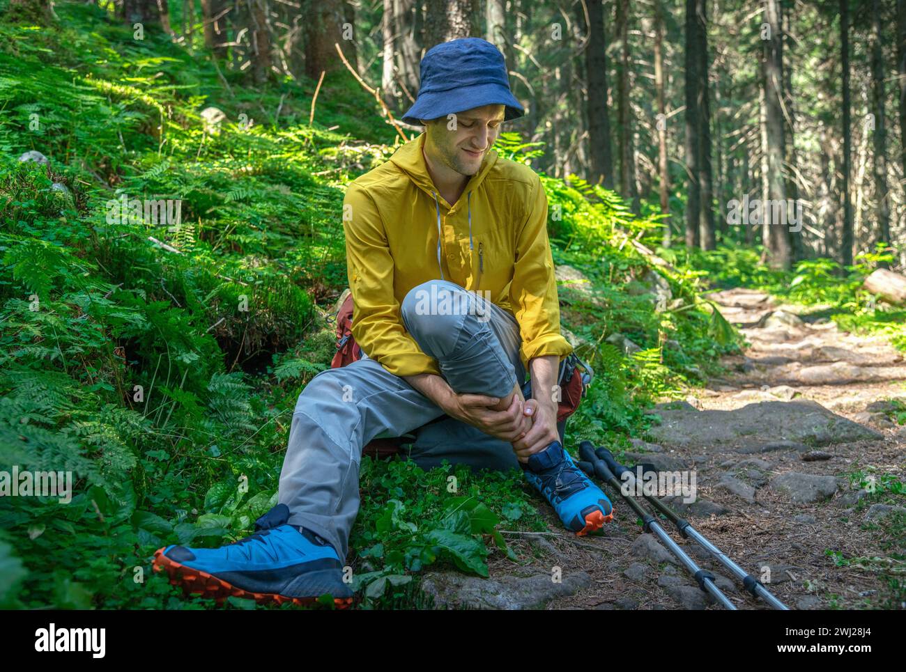 L'uomo con zaino ha problemi con la caviglia spruzzata nella foresta Foto Stock