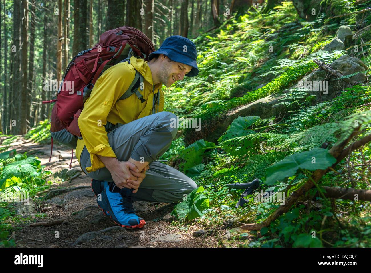 L'uomo con zaino ha problemi con la caviglia spruzzata nelle montagne Foto Stock