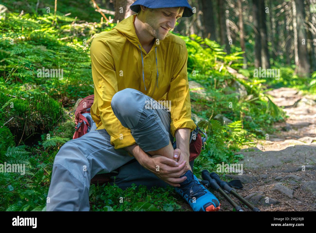 L'uomo con zaino ha problemi con la caviglia spruzzata nella foresta Foto Stock