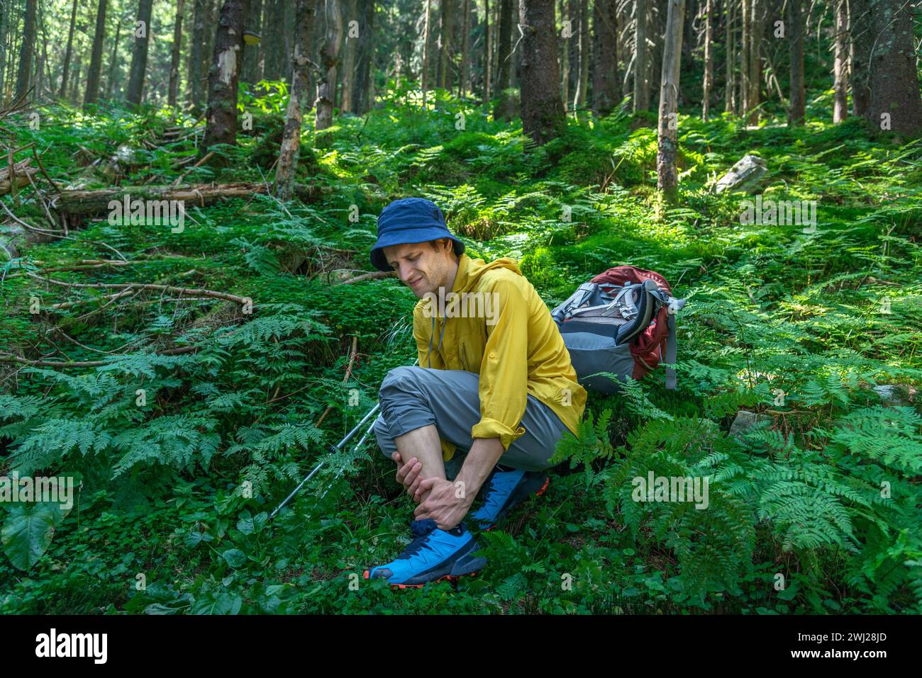 L'uomo con zaino ha problemi con la caviglia spruzzata nella foresta Foto Stock