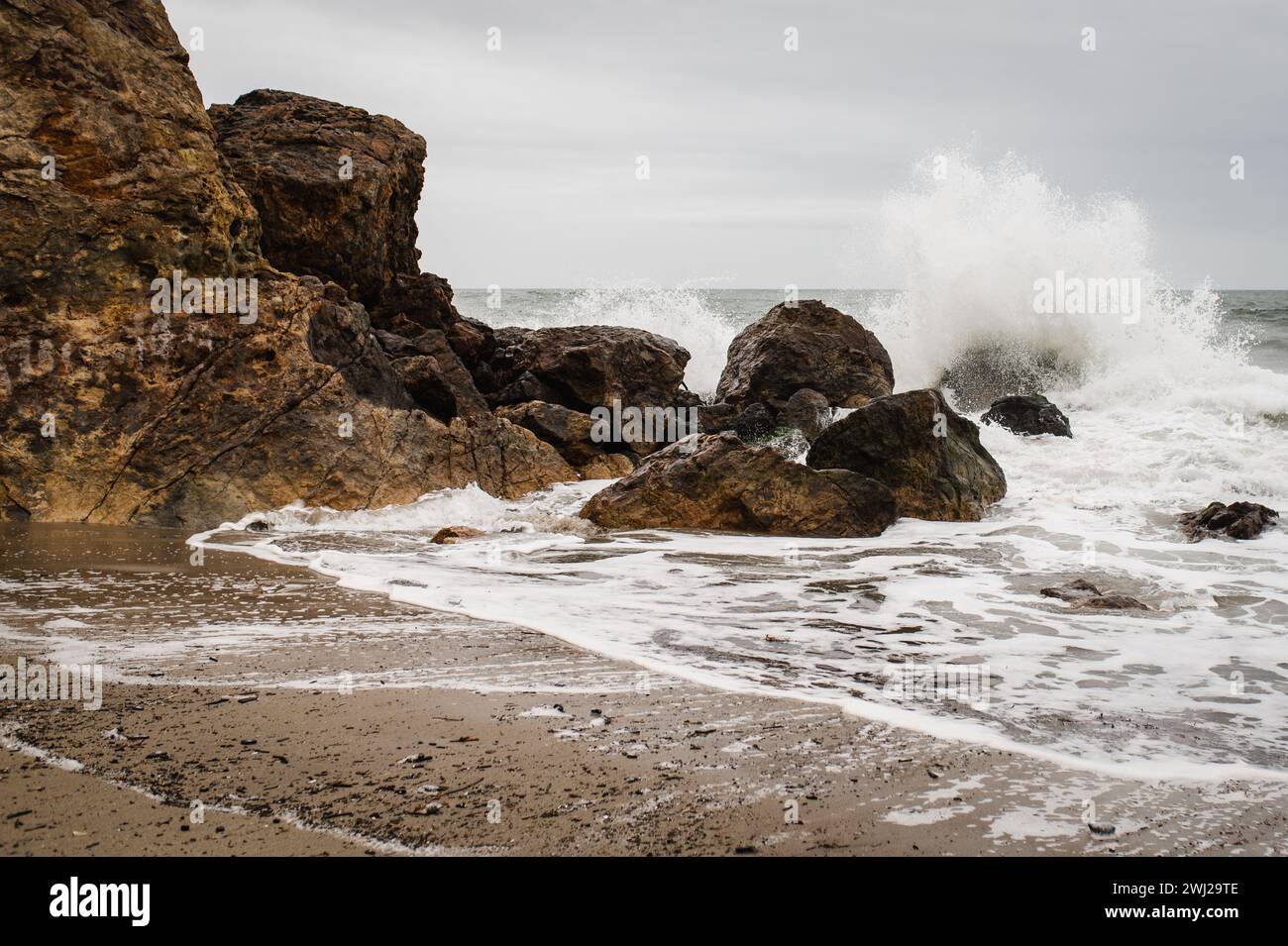 Spiaggia rocciosa con onde che si infrangono Foto Stock