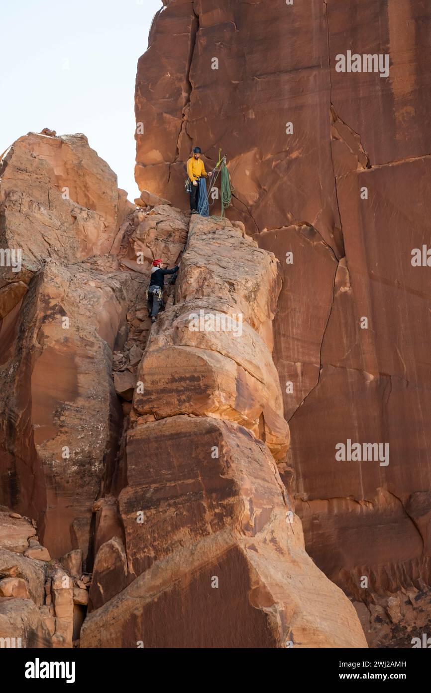 Vista dall'angolo basso degli alpinisti maschi che si arrampicano sulla scogliera rocciosa nel deserto Foto Stock