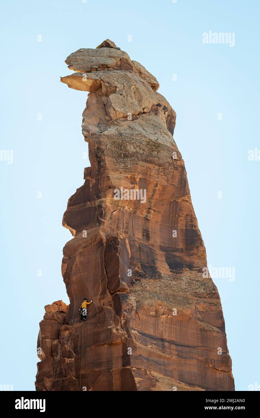 Vista dall'angolo basso dell'alpinista che raggiunge la cima della scogliera rocciosa Foto Stock