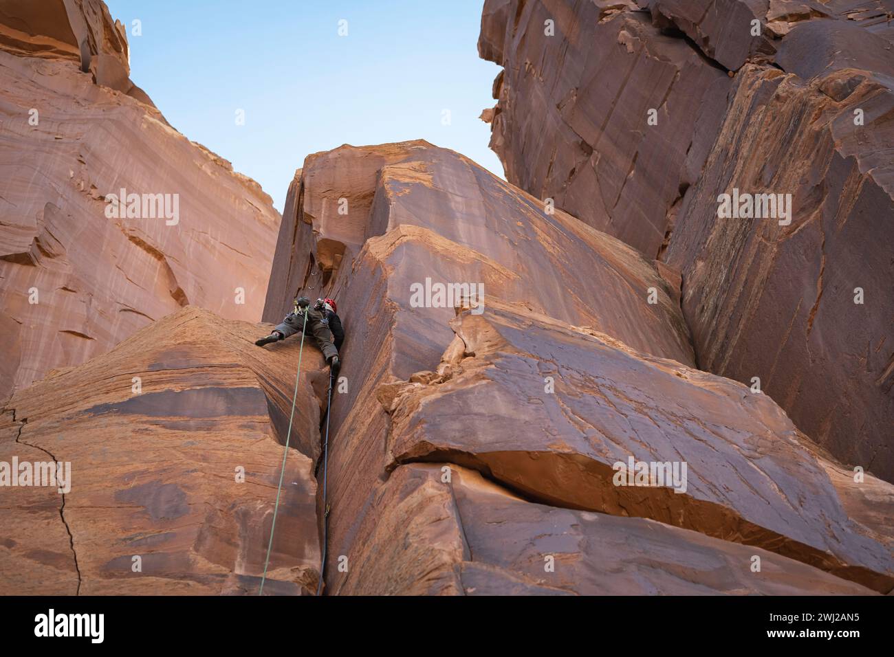 Visuale ad angolo basso dell'uomo determinato che arrampica le rocce sulla scogliera Foto Stock