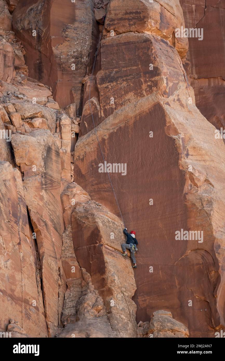 Determinato alpinista che arrampica sulla scogliera rocciosa nel deserto Foto Stock