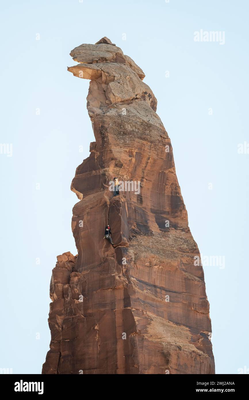 Vista ad angolo basso degli alpinisti che raggiungono la cima della scogliera rocciosa Foto Stock
