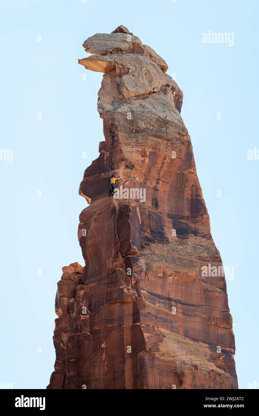 Vista ad angolo basso dell'uomo che sale su una scogliera contro il cielo Foto Stock