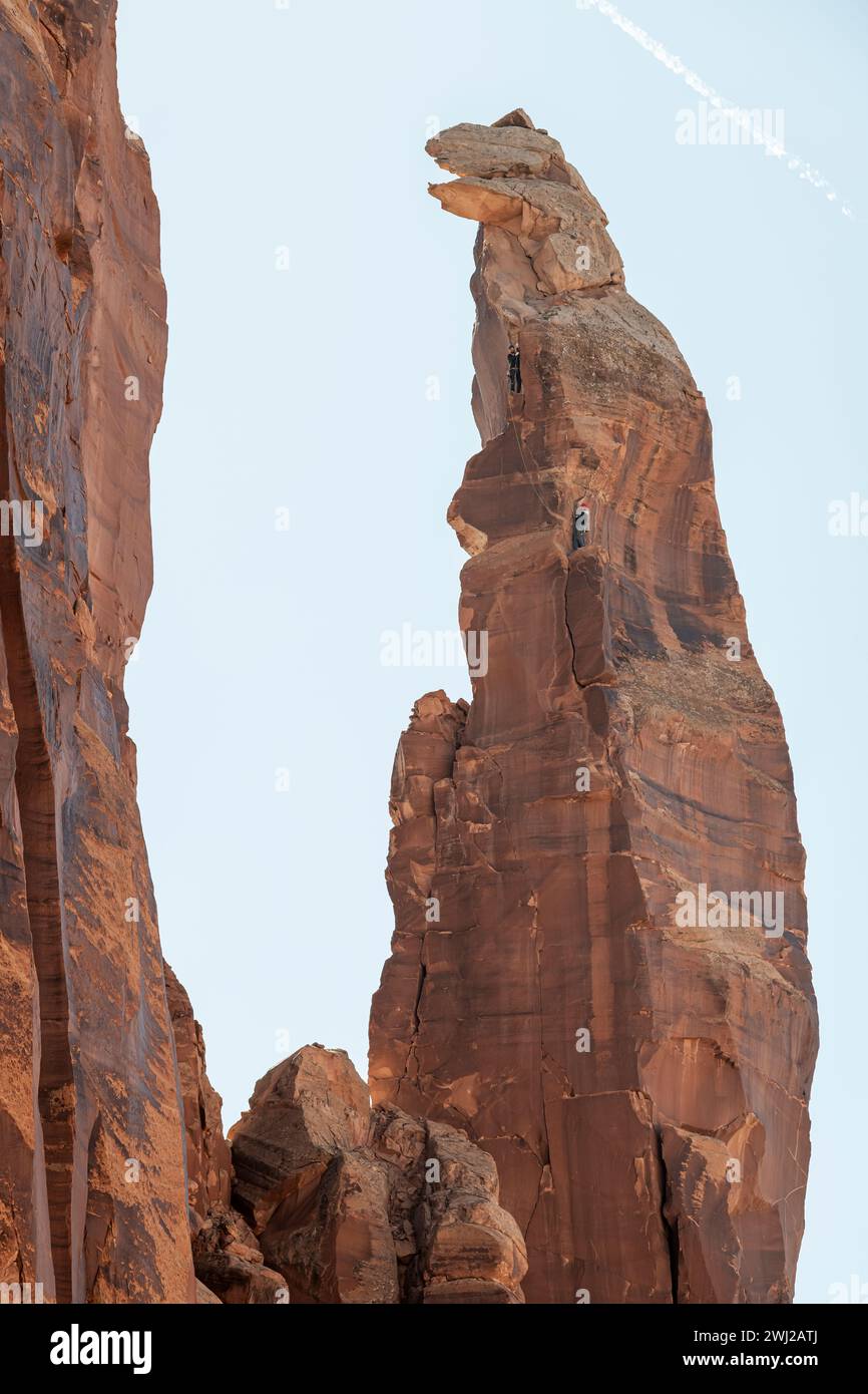 Vista ad angolo basso degli alpinisti che raggiungono la vetta della scogliera rocciosa Foto Stock