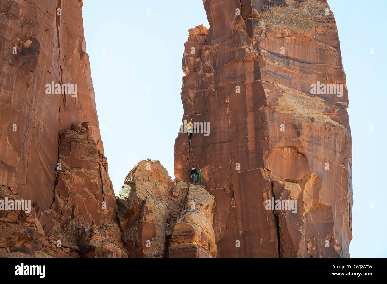 Vista ad angolo basso degli alpinisti che raggiungono la cima della scogliera rocciosa Foto Stock