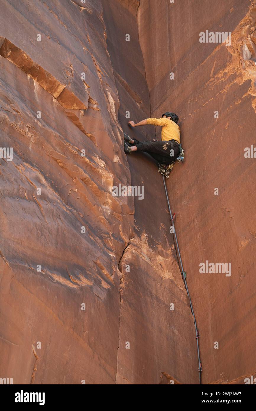 Vista ad angolo basso di un determinato alpinista che sale dalla scogliera rocciosa Foto Stock