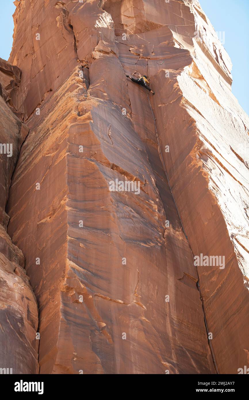 Vista dall'angolo basso dell'alpinista che sale su un'alta scogliera rocciosa Foto Stock
