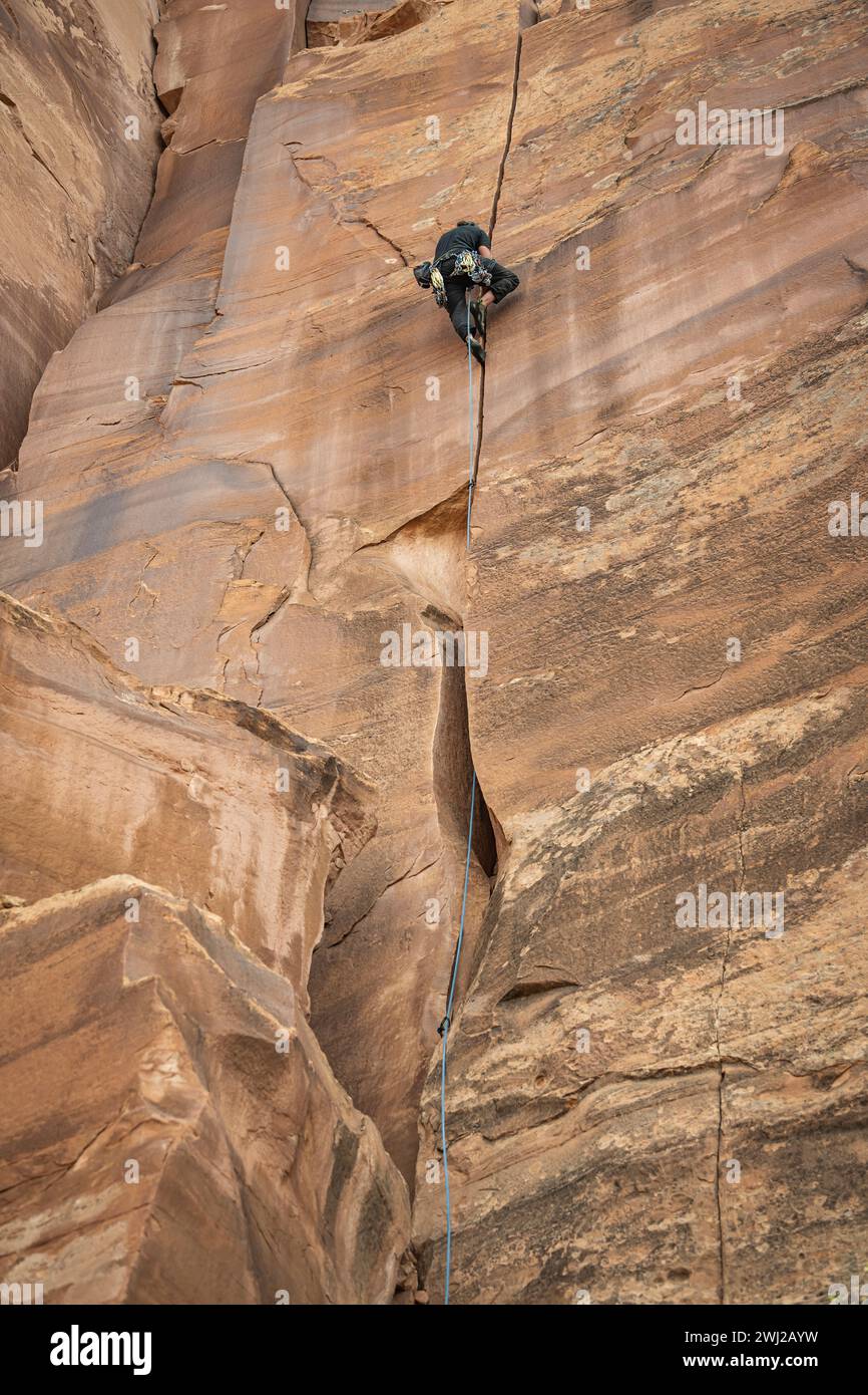 Vista dall'angolo basso di un determinato alpinista che arrampica sulla scogliera nel deserto Foto Stock