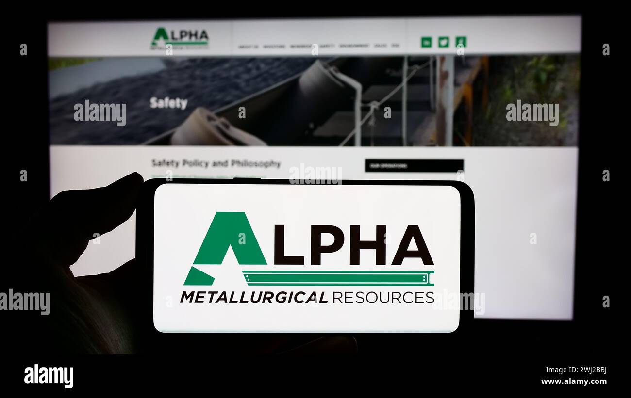 Persona che detiene un cellulare con il logo della società mineraria statunitense Alpha Metallurgical Resources Inc. Di fronte alla pagina web aziendale. Mettere a fuoco il display del telefono. Foto Stock
