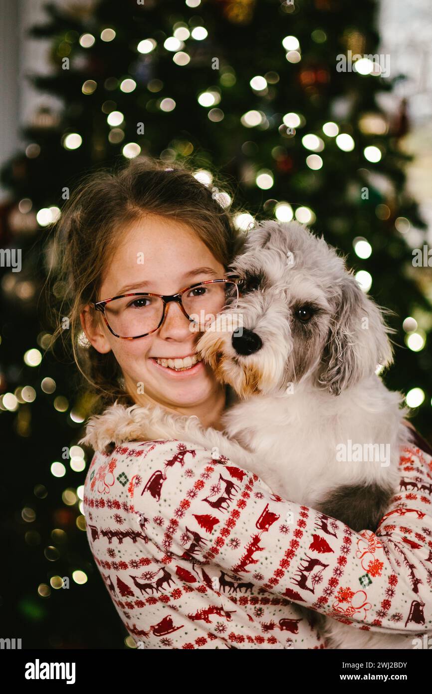 Tween ragazza in occhiali si accosta con il cucciolo di schnauzer a Natale Foto Stock