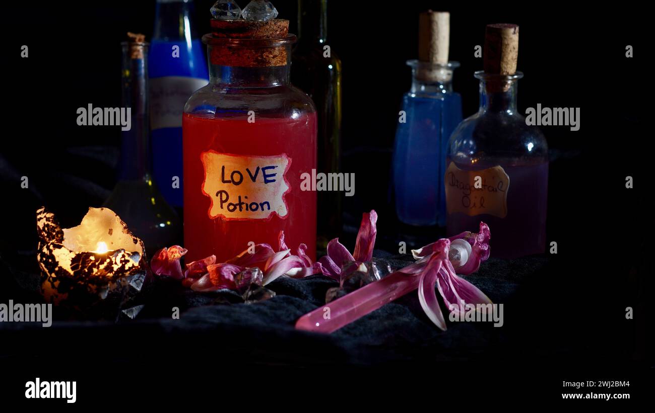 Bottiglie in vetro riempite con varie pozioni. Pozione d'amore, una candela, fiori. Stregoneria. Malattia d'amore. Foto Stock