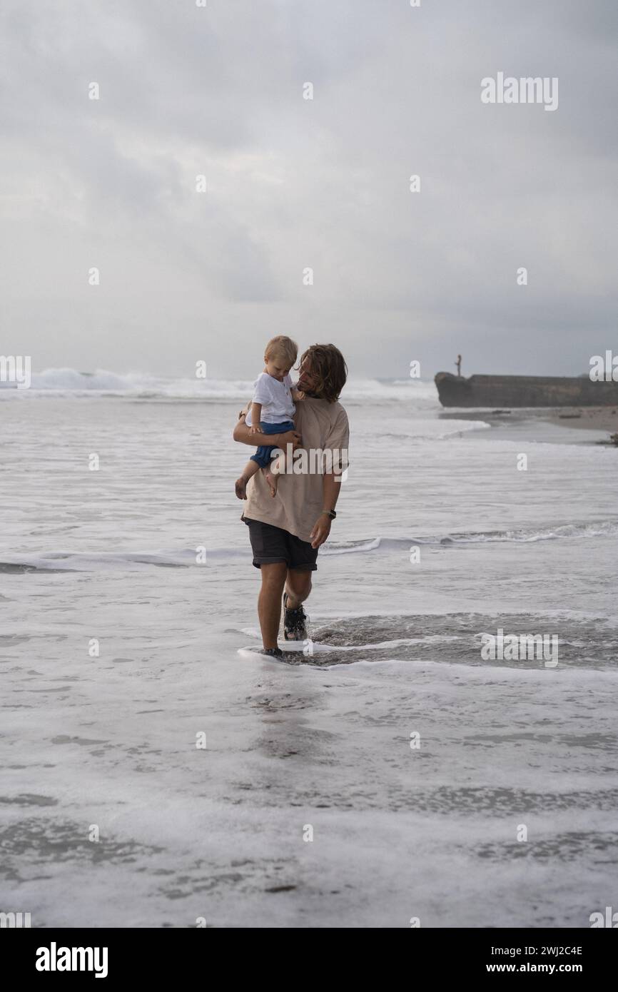 Padre che cullano il figlio infantile sulla spiaggia Foto Stock