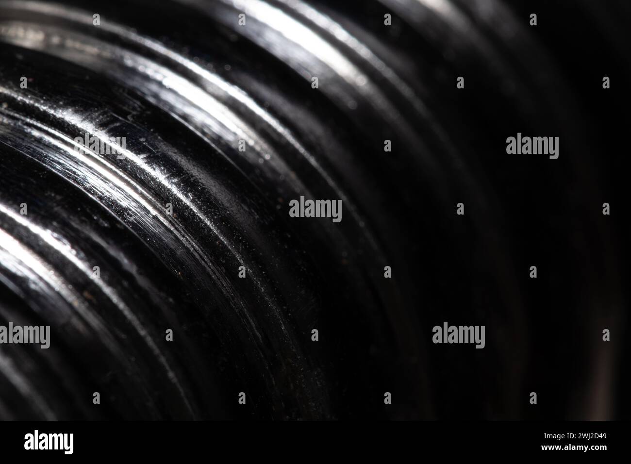 Primo piano della filettatura di una vite metallica su sfondo nero, metallo testurizzato, macro astratta Foto Stock
