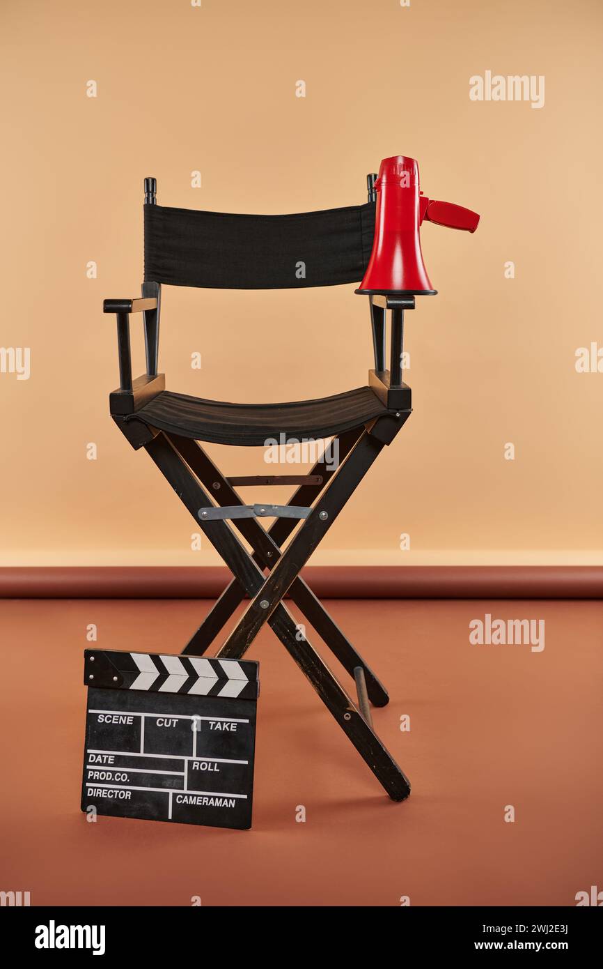 la sedia del regista è alta, adornata da un megafono e da un clapper board, concetto cinematografico Foto Stock
