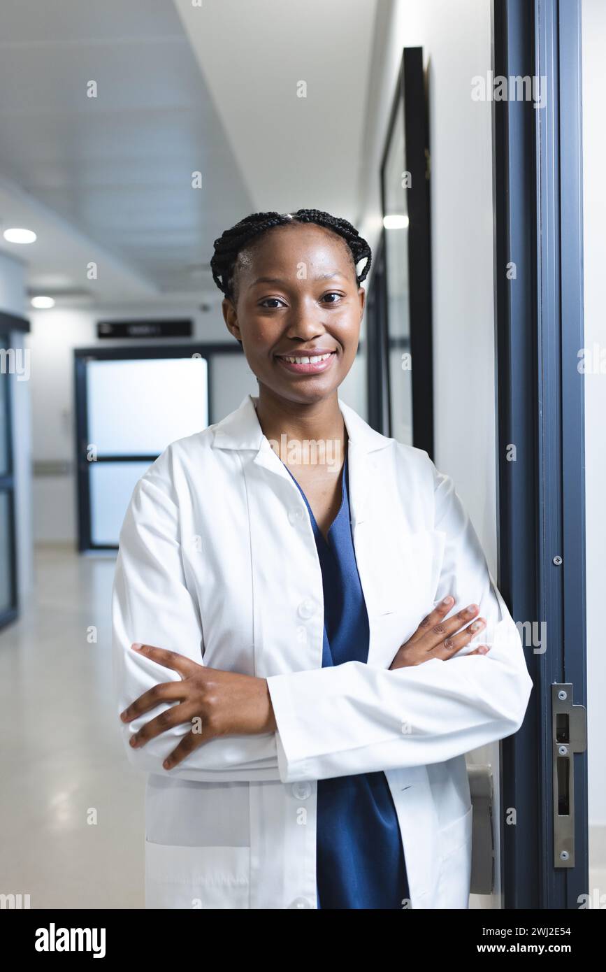 Ritratto di felice medico afro-americano che indossa il cappotto da laboratorio nel corridoio dell'ospedale Foto Stock