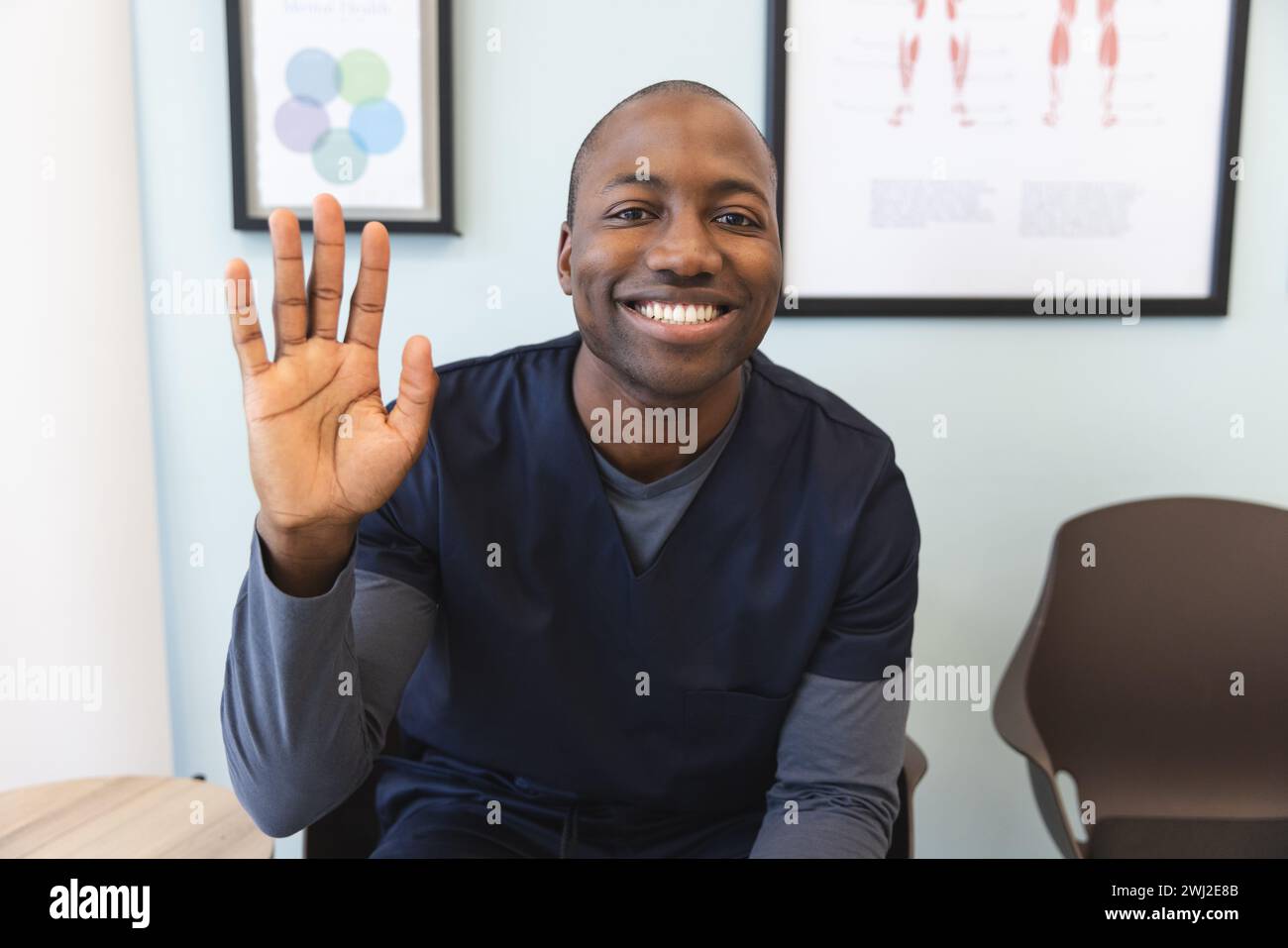 Felice afro-americano maschio medico avere videochiamata in sala d'attesa in ospedale Foto Stock