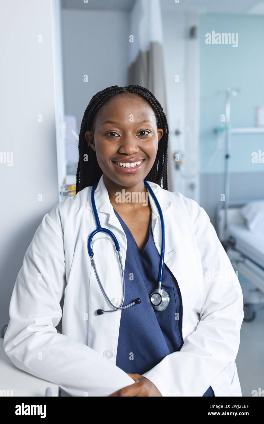 Ritratto di felice medico afroamericano che indossa camice da laboratorio e stetoscopio in camera d'ospedale Foto Stock