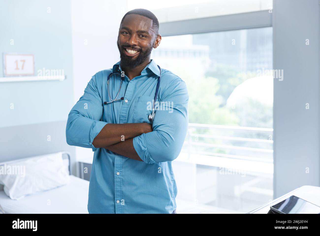 Ritratto del medico maschio afro-americano felice che indossa una camicia blu nella stanza d'ospedale, copia spazio Foto Stock