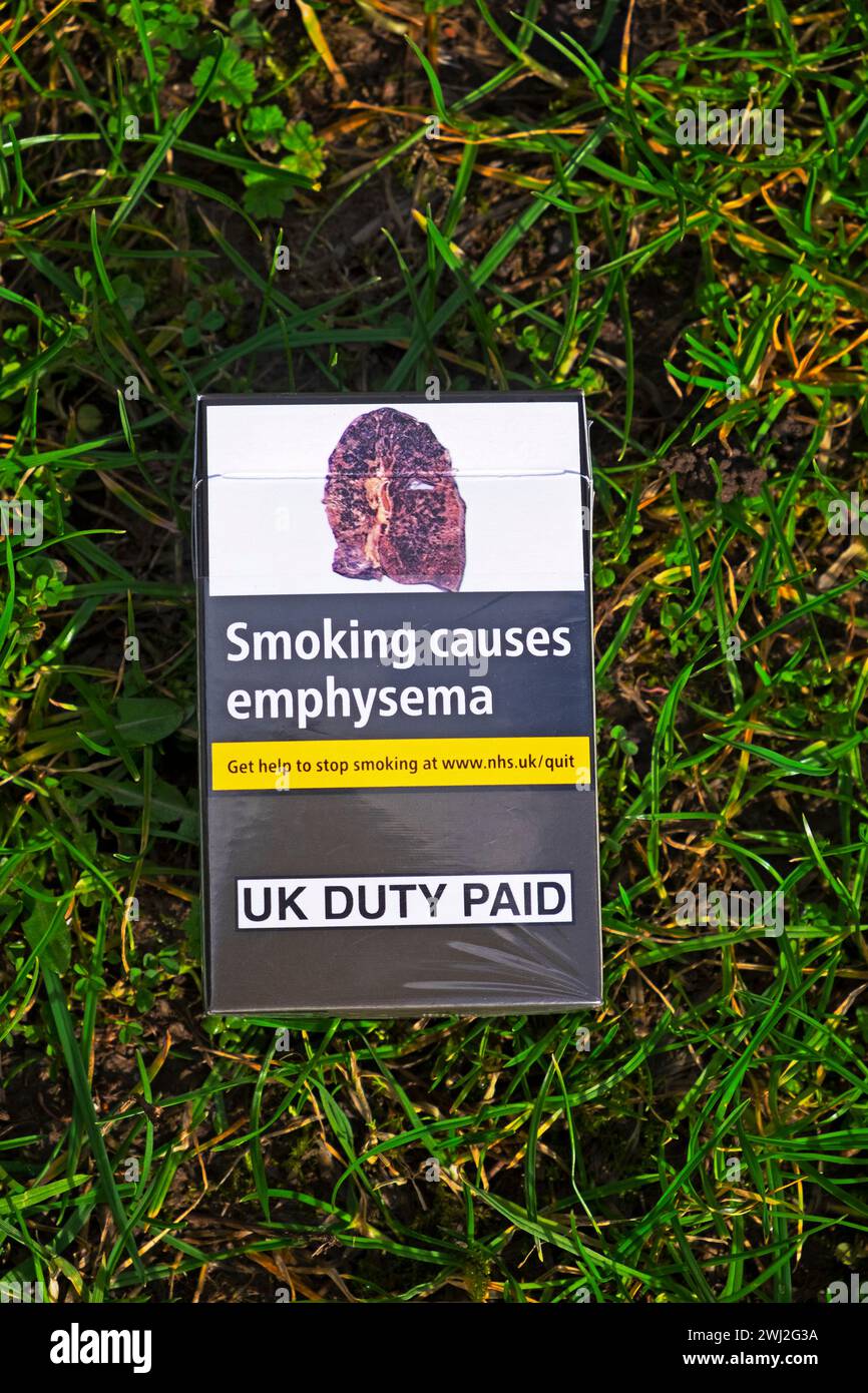 Un pacchetto di sigarette scartato su sfondo erba con polmone malato causato dal fumo che mostra enfisema avvertimento nel Regno Unito KATHY DEWITT Foto Stock