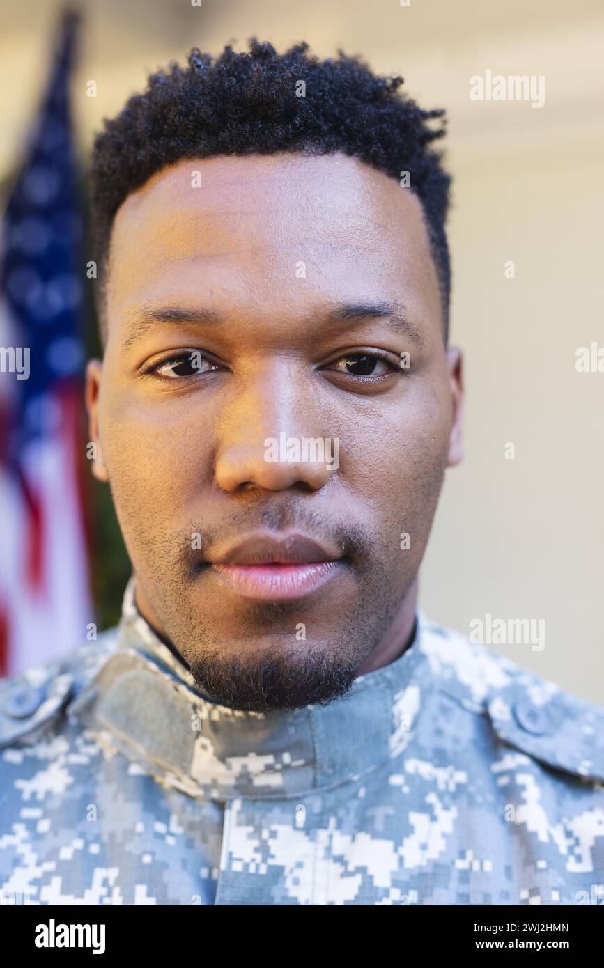 Un soldato afroamericano focalizzato affronta da vicino fuori casa con la bandiera degli stati uniti e lo spazio per le copie Foto Stock