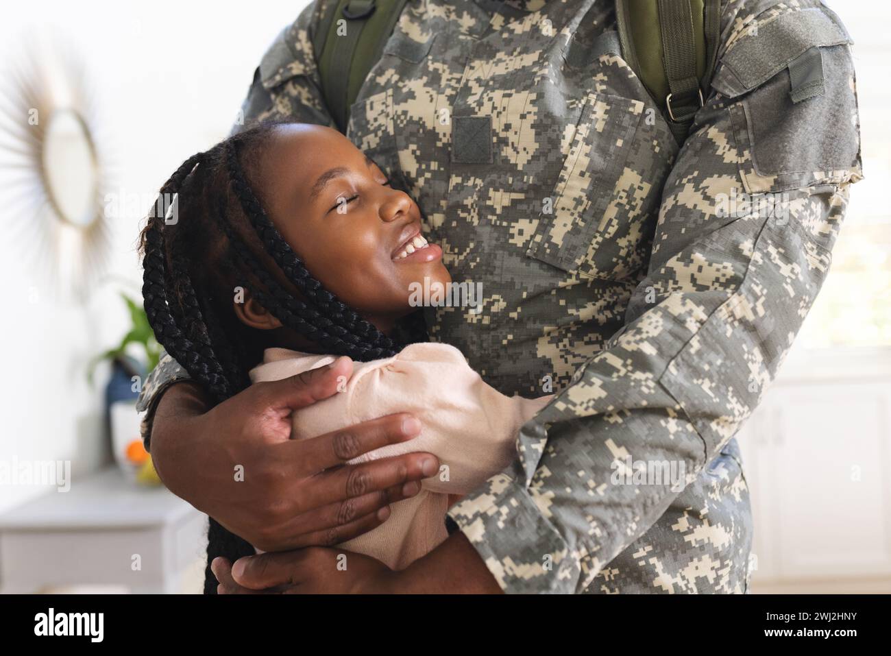 Felice soldato afroamericano che abbraccia la figlia a casa, copia spazio Foto Stock