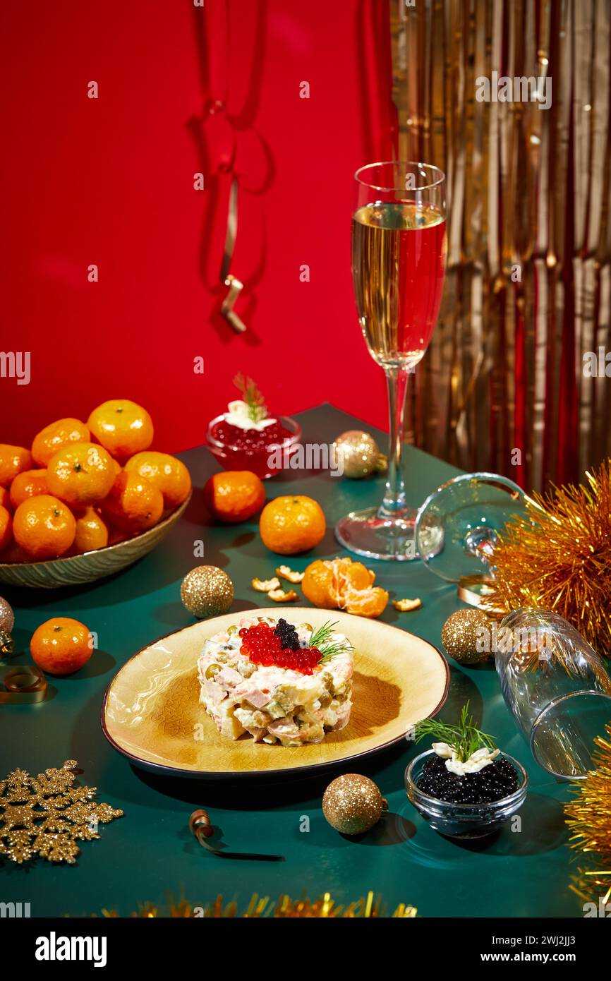 Tavolo di Capodanno o di Natale per feste in stile russo con champagne in bicchiere, mandarini e insalata Olivier in porzioni Foto Stock